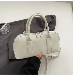 Detalle del bolso bandolera de cuero blanco crema con cremalleras de plata y logo