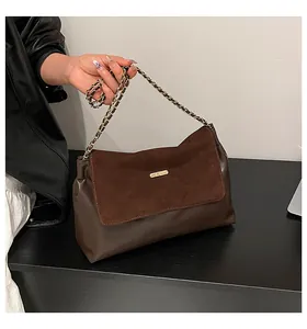 Close-up of brown suede and leather texture with golden chain on a luxury handbag