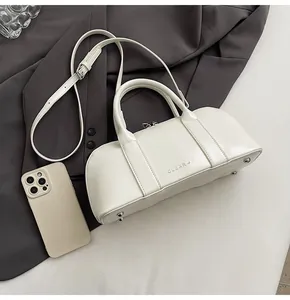 Detalle del bolso Boston de piel crema con tachuelas metálicas y correa ajustable