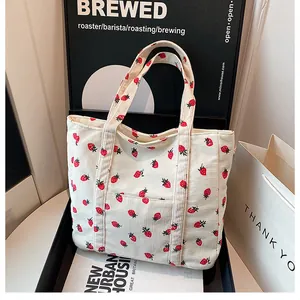 Detail of corduroy tote bag featuring red strawberry prints and a front pocket