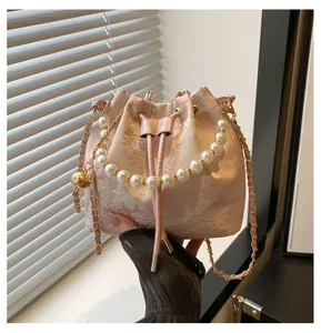 Detail of light pink bucket bag with floral jacquard fabric and pearl handle