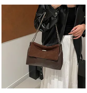 Close-up of dark brown suede and leather splicing detail on a chain shoulder bag