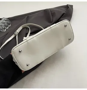 Detalle de la parte inferior de un bolso blanco con pies protectores metálicos plateados
