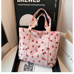 Detail of pink corduroy tote bag with strawberry pattern and soft ribbed texture