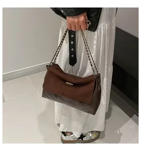 Detail of dark brown patchwork shoulder bag featuring chain strap and suede texture
