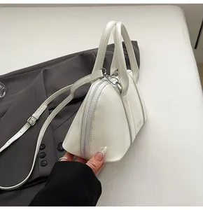 Detalle de un bolso de mano blanco con forma de concha en cuero PU y piezas metálicas