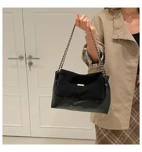Detail of black patchwork chain bag with gold buckle on trench coat outfit
