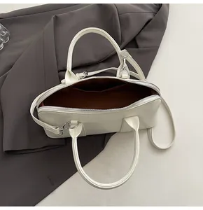Vista superior del bolso Boston en cuero crema con forro marrón y correa ajustable