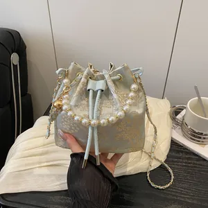 Elegant jacquard bucket bag with pearl handle and gold chain strap on soft fabric