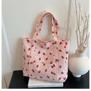 Detailed texture of pink corduroy tote bag with vibrant red strawberry pattern