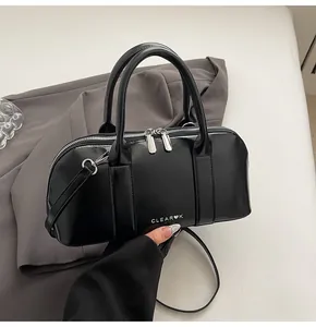 Primer plano del bolso de cuero PU negro brillante con logo Clear K y herrajes plateados