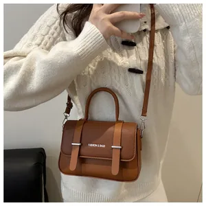 Détail d'un sac boîte en cuir marron avec doubles sangles et boucles en métal argenté