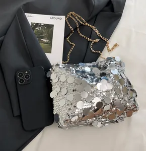 Detailansicht einer silbernen Paillettentasche mit Goldkette neben einem Smartphone