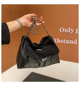Detailed close-up of a black leather hobo bag with suede flap and gold chain strap