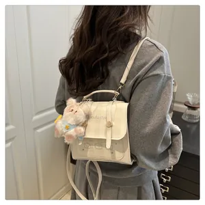 Detail of cream plaid mini backpack with plush bunny charm and artistic graphic design