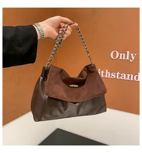 Detail of the brown patchwork shoulder bag with leather texture and metal chain strap