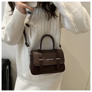 Détail du sac boîte marron foncé avec rabat texturé et boucles métalliques élégantes