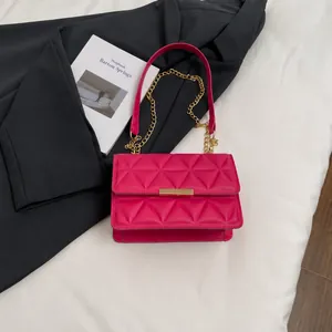 Detail of rose pink quilted crossbody bag with gold lock and chain beside a smartphone