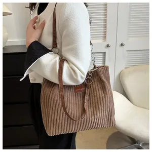 Close-up of brown corduroy tote bag showing vertical texture and fashion leather tag