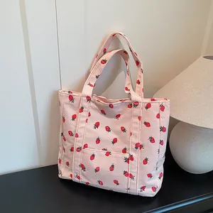 Pink corduroy strawberry tote bag with large capacity for women on a stylish desk