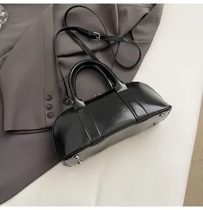 Detalle de bolso Boston negro pulido con pies plateados y correa desmontable