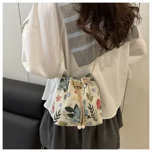 Detail of floral embroidery on a linen bucket bag with gold chain and pearl tassels