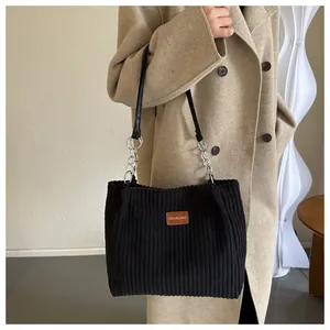 Close-up of black corduroy tote bag with fashion leather patch and chain strap detail