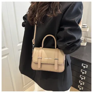 Détail du sac boîte beige montrant la texture du cuir grainé et boucles en métal