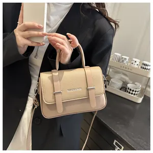 Vue détaillée du sac boîte en cuir beige porté avec un blazer noir pour montrer la taille