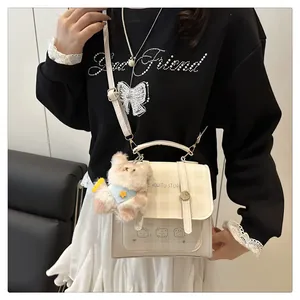 Detail of beige plaid handbag with cute bear charm and logo shown on model