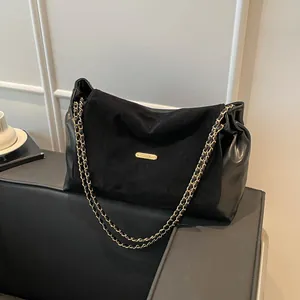 Elegant black chain shoulder bag with suede flap and gold hardware on a minimalist background