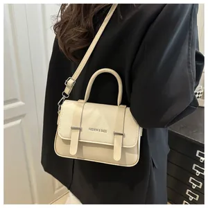 Gros plan du sac bandoulière beige en cuir grainé avec boucles argentées et rabat de fermeture