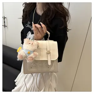 Detailed shot of cream checkered crossbody bag with cute bear prints and plush charm