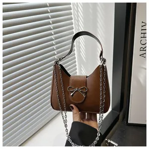Détail d'un sac demi-lune en cuir marron avec boucle nœud argenté et bandoulière