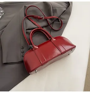 Detalle de bolso de cuero granate con pies protectores plateados y textura suave