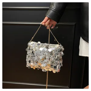 Dettaglio di paillettes giganti argento e oro luccicanti su una borsa a catena
