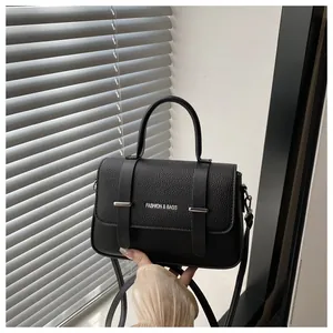 Détail du sac boîte noir avec texture cuir et garnitures argentées sous ombres de fenêtre