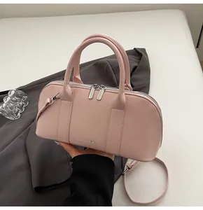 Detalle de bolso Boston rosa suave sobre blazer gris con cremallera plateada