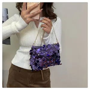 Dettaglio della borsa di paillettes viola con catena dorata su modella in maglia bianca
