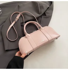 Detalle de bolso bowling de cuero rosa con asas superiores y correa ajustable