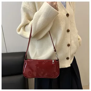 Detail shot of a red patent leather baguette bag featuring a sleek glossy finish and silver zip