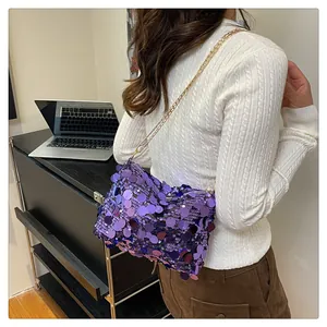 Dettaglio della borsa a tracolla con paillettes viola e catena dorata su modella
