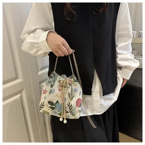 Detail view of cotton linen bucket bag with floral embroidery and gold chain strap