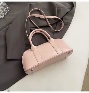 Detalle del bolso de cuero rosa claro con asas dobles y tachuelas de fondo plateadas