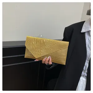 Close-up of golden envelope clutch featuring a premium crocodile embossed texture