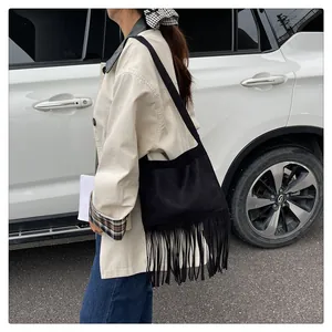Détail d'un sac à bandoulière en daim noir avec de longues franges sur un modèle extérieur