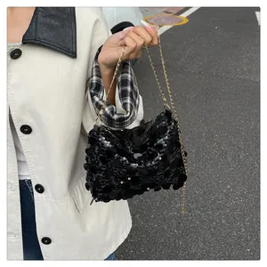 Dettaglio di una borsa a tracolla con paillettes nere e catena dorata su una modella