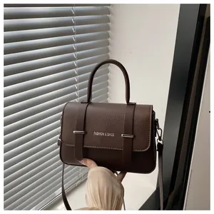 Détail du sac à main en cuir marron foncé avec logo argenté et doubles sangles décoratives