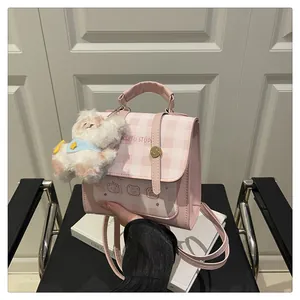 Detailed view of pink plaid mini backpack with bear pattern and fluffy dog charm