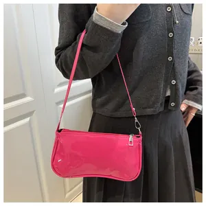 Detail view of hot pink patent leather baguette bag worn on shoulder in y2k style